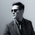 Black and white head shot of millennial man wearing sunglasses and a suit